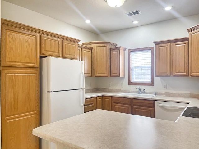 kitchen featuring white appliances, a peninsula, visible vents, recessed lighting, and a sink