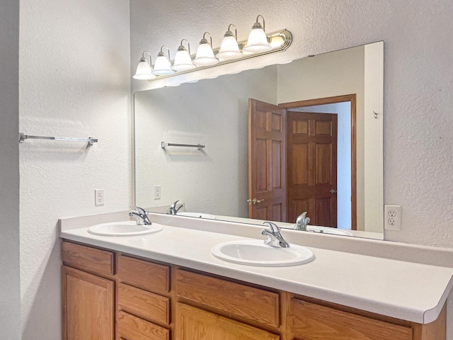 full bath with double vanity, a sink, and a textured wall