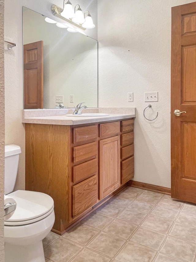 bathroom with tile patterned flooring, toilet, vanity, and baseboards