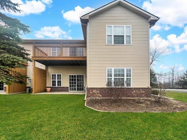 rear view of property featuring a patio, a balcony, central air condition unit, brick siding, and a yard