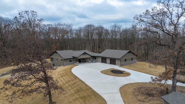 W7181 Duck Creek Ave, Westfield, WI 53964 - view of front of property featuring a front yard, stone siding, curved driveway, an attached garage, and a view of trees