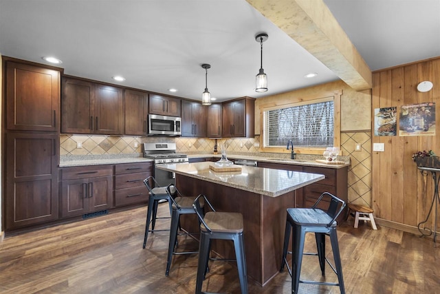 W7181 Duck Creek Ave, Westfield, WI 53964 - kitchen with a breakfast bar area, a kitchen island, appliances with stainless steel finishes, a sink, and dark wood-style floors