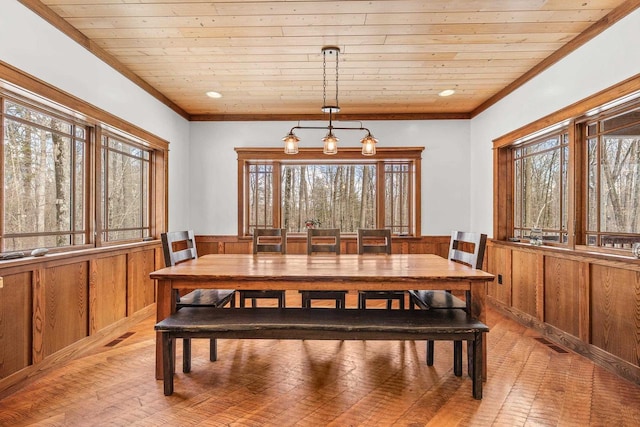 3853 County Rd E, Junction City, WI 54443 - dining area featuring a wainscoted wall, light wood-style floors, wooden walls, crown molding, and wood ceiling