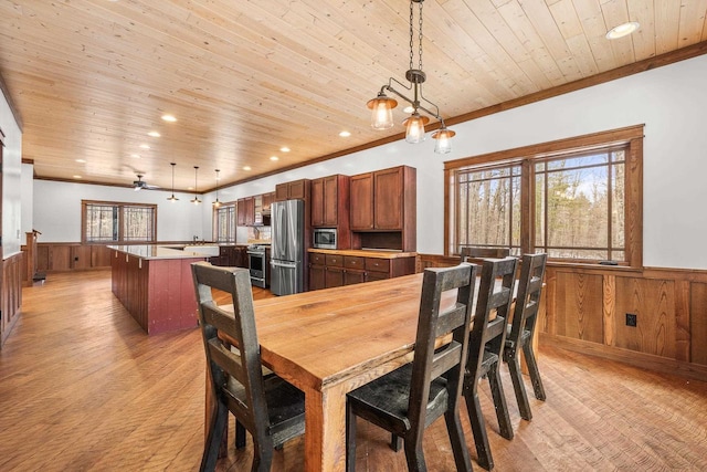 3853 County Rd E, Junction City, WI 54443 - dining space featuring a wainscoted wall, light wood-style flooring, wooden walls, and crown molding