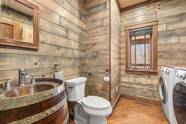 3853 County Rd E, Junction City, WI 54443 - half bath with separate washer and dryer, wood walls, toilet, baseboards, and wood finished floors