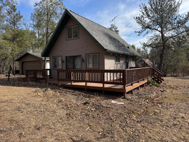 back of property featuring a garage and a deck