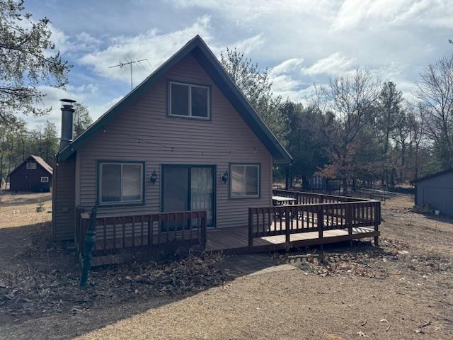 back of house with a chimney and a deck