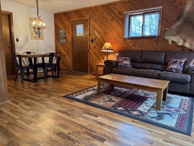 living area with a chandelier, wood finished floors, and wooden walls