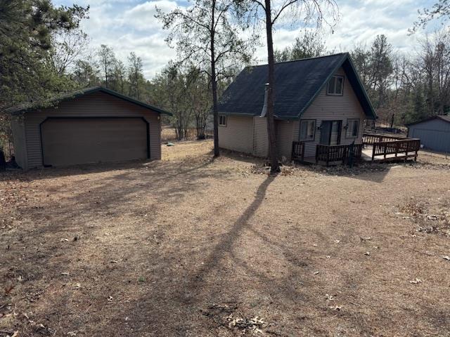 view of home's exterior with a detached garage, an outdoor structure, and a deck
