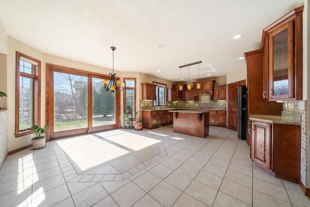 3895 Shorebird Ct, Oshkosh, WI 54904 - kitchen with tasteful backsplash, glass insert cabinets, a center island, freestanding refrigerator, and light tile patterned flooring