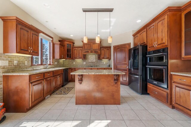 3895 Shorebird Ct, Oshkosh, WI 54904 - kitchen with light stone countertops, brown cabinets, a center island, and black appliances