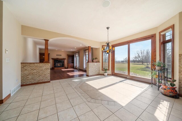 3895 Shorebird Ct, Oshkosh, WI 54904 - unfurnished dining area with light tile patterned floors, decorative columns, an inviting chandelier, arched walkways, and visible vents