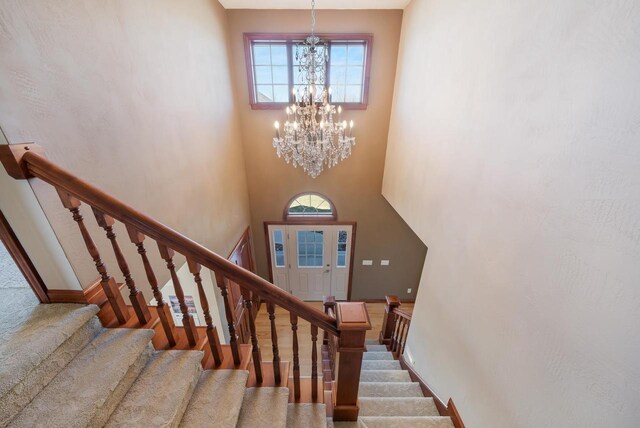 3895 Shorebird Ct, Oshkosh, WI 54904 - stairs with baseboards, wood finished floors, an inviting chandelier, and a towering ceiling