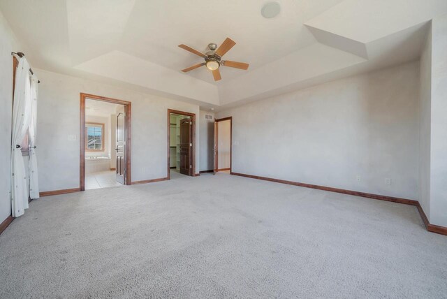 3895 Shorebird Ct, Oshkosh, WI 54904 - unfurnished bedroom with a tray ceiling, baseboards, connected bathroom, and light colored carpet