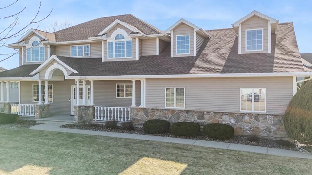 3895 Shorebird Ct, Oshkosh, WI 54904 - view of front facade featuring a front yard, stone siding, a shingled roof, and covered porch