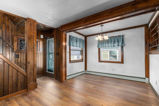 2963 Sunset Point Ln, Oshkosh, WI 54904 - unfurnished room featuring a notable chandelier, wooden walls, a textured ceiling, a baseboard radiator, and wood finished floors