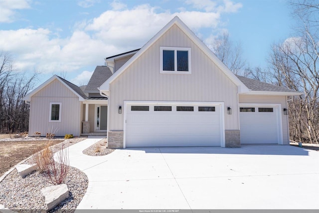 view of front of house featuring a shingled roof, driveway, a garage, and stone siding