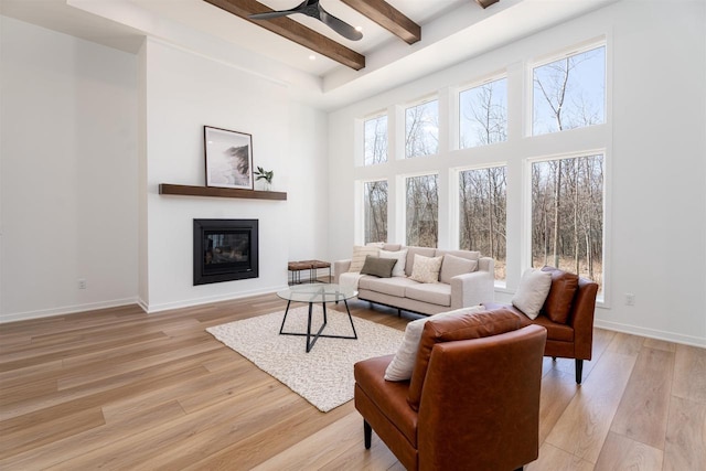 living room featuring light wood-style flooring, baseboards, and beam ceiling