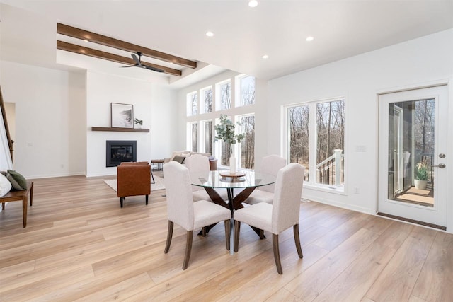 dining area with beamed ceiling, light wood-style flooring, and plenty of natural light