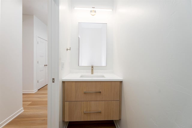 bathroom featuring vanity, baseboards, and wood finished floors