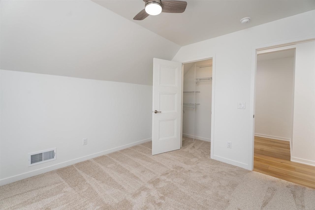 unfurnished bedroom featuring visible vents, baseboards, carpet, and vaulted ceiling