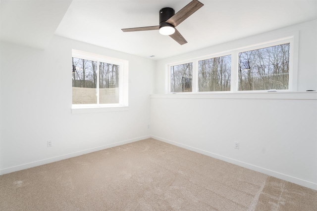 spare room with carpet flooring, baseboards, a ceiling fan, and a wealth of natural light
