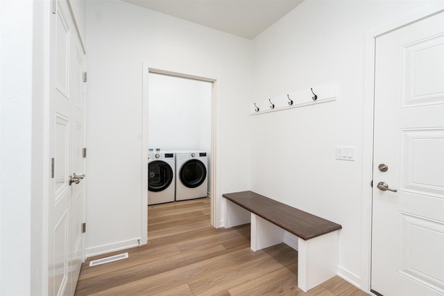 mudroom featuring light wood finished floors, visible vents, and washer and clothes dryer