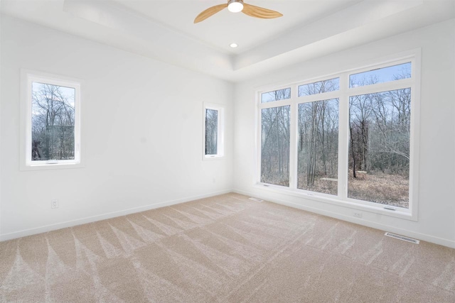 carpeted empty room featuring baseboards, recessed lighting, visible vents, a tray ceiling, and ceiling fan