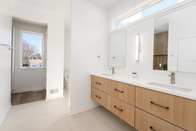 full bath with double vanity, visible vents, a sink, and toilet
