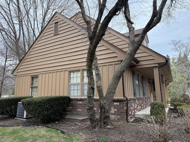 view of side of home with brick siding and central AC unit