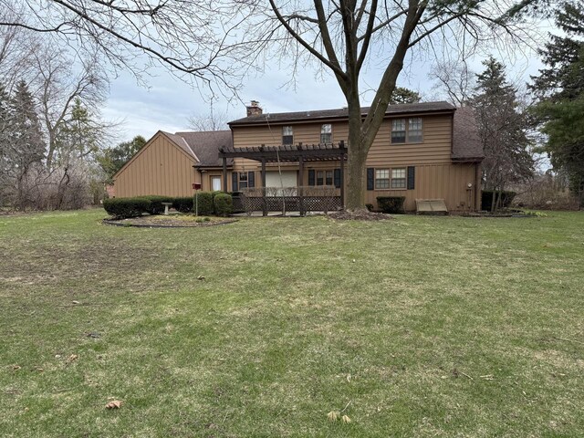 rear view of property featuring a chimney, roof with shingles, a lawn, and a pergola