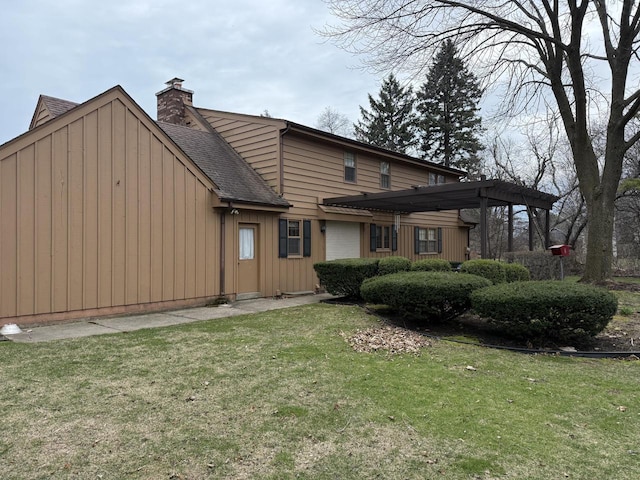 rear view of house featuring board and batten siding, roof with shingles, a chimney, and a lawn