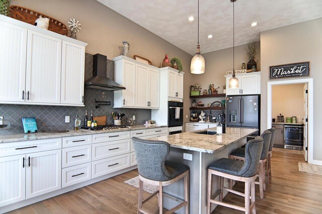 1817 Arboretum Dr, Janesville, WI 53548 - kitchen with a sink, wall chimney exhaust hood, wine cooler, light wood finished floors, and black appliances
