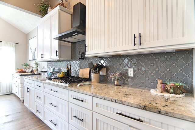 1817 Arboretum Dr, Janesville, WI 53548 - kitchen with wall chimney exhaust hood, light stone countertops, stainless steel gas stovetop, vaulted ceiling, and backsplash