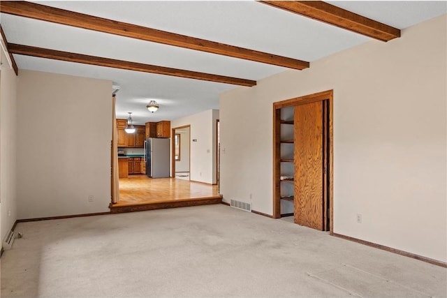 unfurnished living room featuring beamed ceiling, visible vents, baseboards, and light carpet