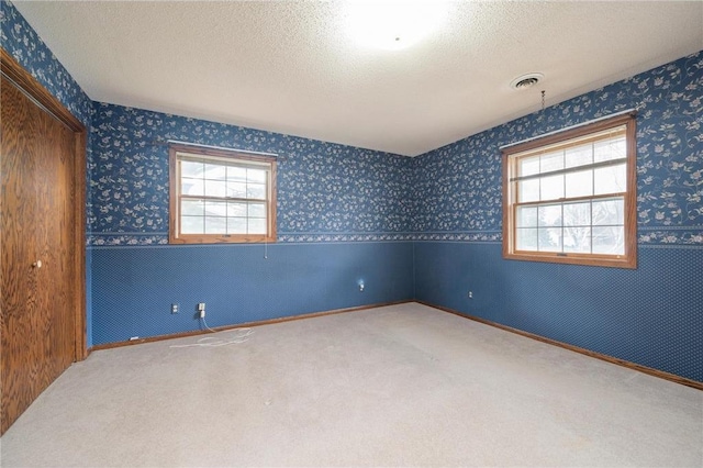 unfurnished room featuring wallpapered walls, visible vents, and carpet floors