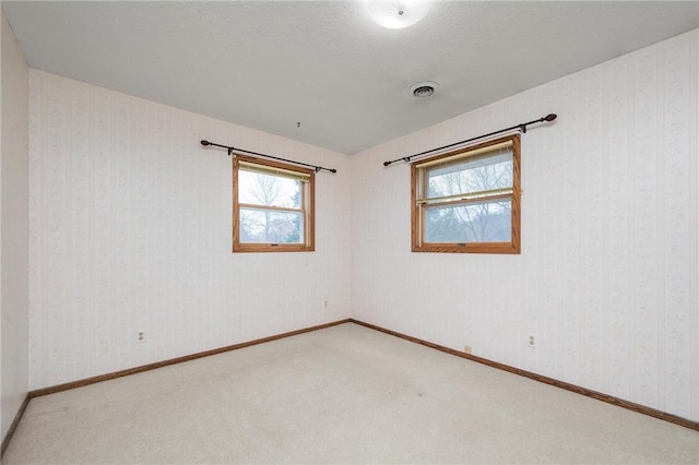 unfurnished room with visible vents, plenty of natural light, and carpet flooring