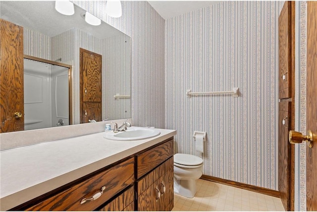 bathroom featuring wallpapered walls, an enclosed shower, toilet, vanity, and baseboards