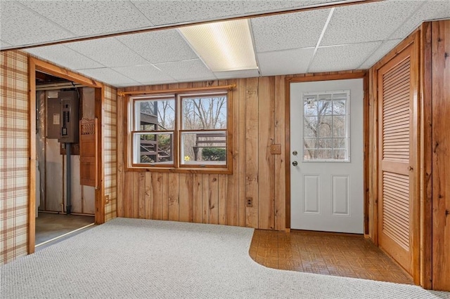 foyer entrance featuring wooden walls, a paneled ceiling, electric panel, and a healthy amount of sunlight