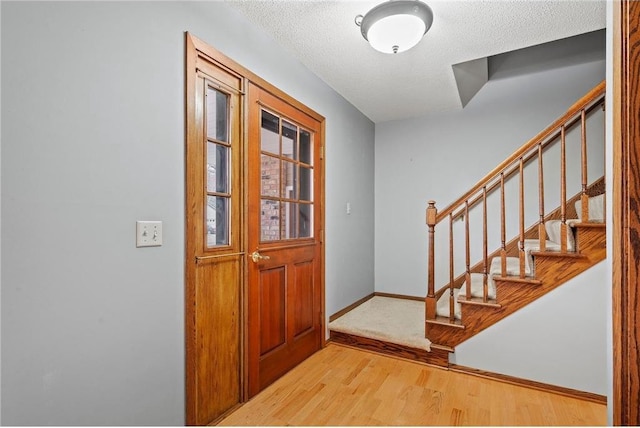foyer entrance with stairs, light wood-style floors, and baseboards