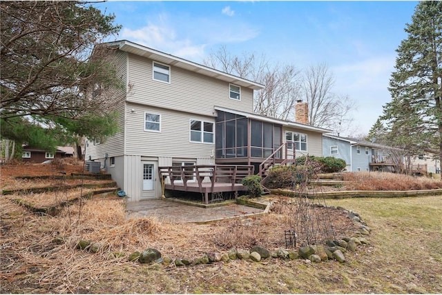 rear view of property featuring a chimney, a wooden deck, a sunroom, and central AC unit