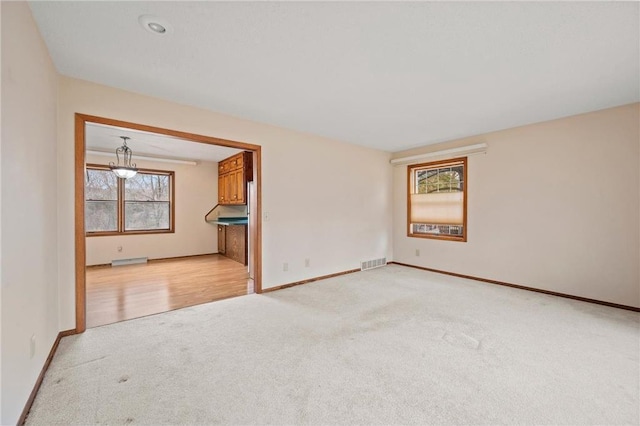 empty room with baseboards, visible vents, and light colored carpet