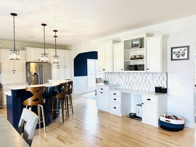 W330S8380 Isabelle Dr, Mukwonago, WI 53149 - kitchen featuring stainless steel fridge, white cabinetry, open shelves, light wood-style floors, and a kitchen bar