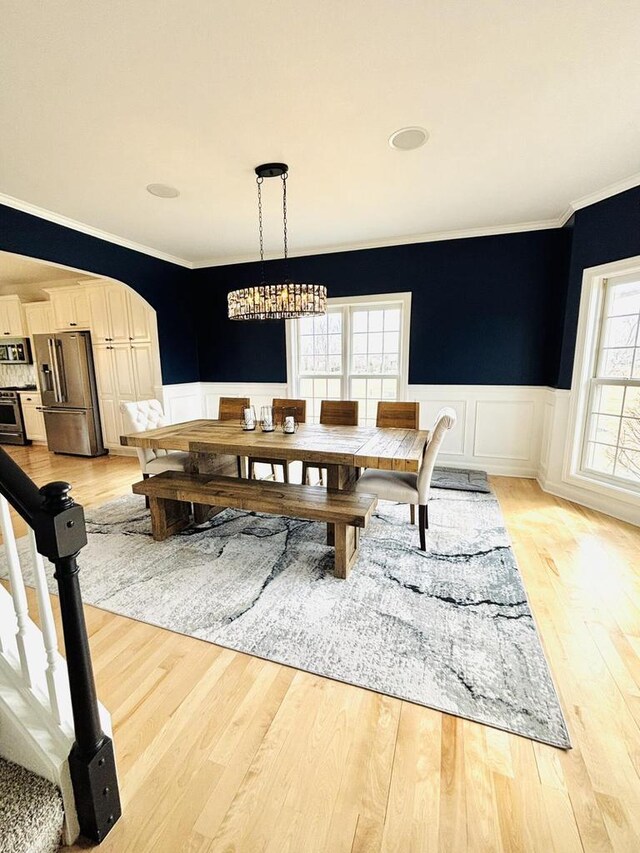 W330S8380 Isabelle Dr, Mukwonago, WI 53149 - dining space with arched walkways, light wood-type flooring, ornamental molding, and wainscoting