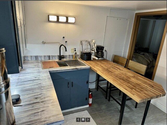 kitchen featuring butcher block countertops, a sink, and blue cabinets