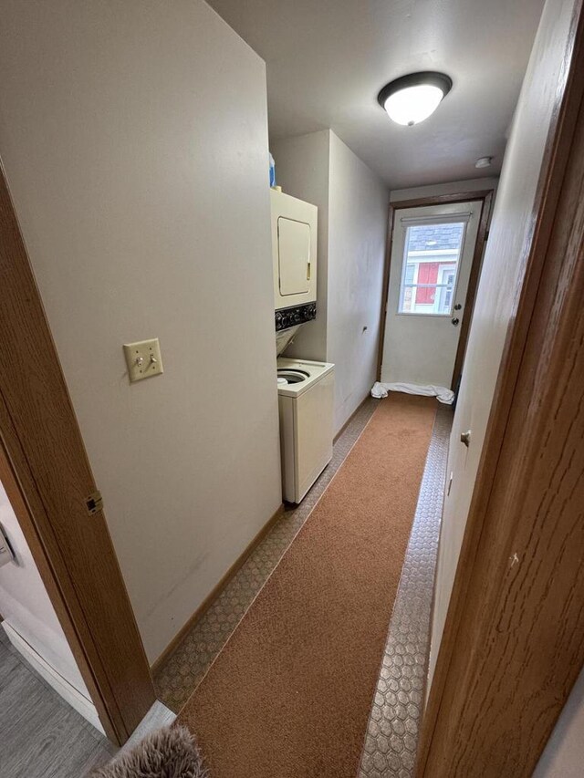 washroom featuring laundry area, stacked washer and clothes dryer, and baseboards
