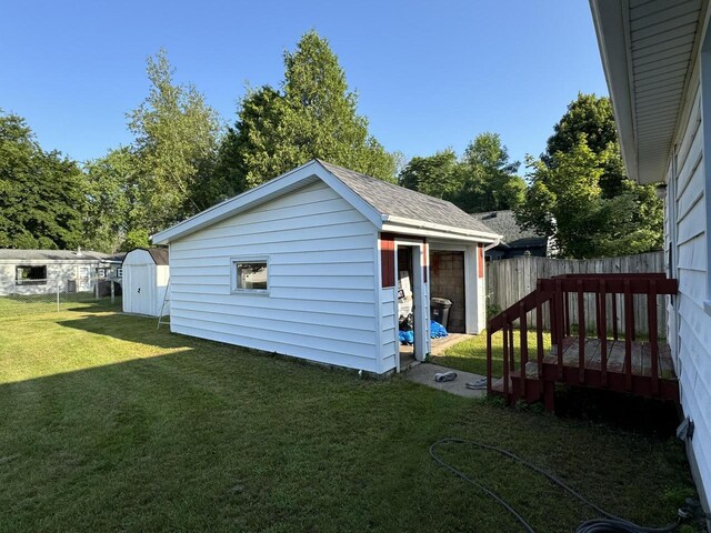 exterior space featuring an outdoor structure, fence, and a lawn