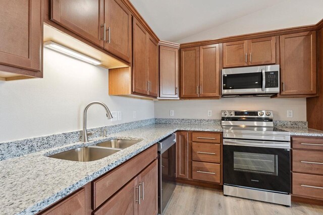 2465 Russell Ct, Reedsburg, WI 53959 - kitchen with a sink, appliances with stainless steel finishes, vaulted ceiling, light wood-style flooring, and light stone counters