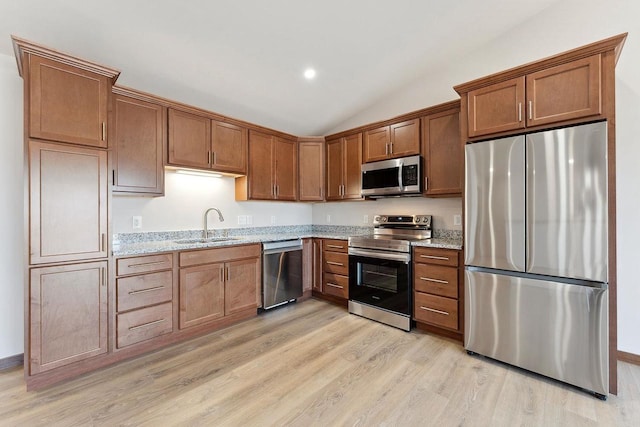 2465 Russell Ct, Reedsburg, WI 53959 - kitchen with light wood-style flooring, vaulted ceiling, light stone counters, a sink, and stainless steel appliances
