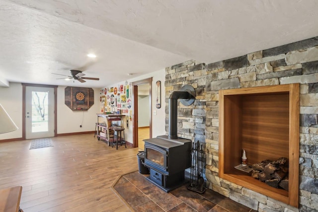 N3759 Airport Rd, Cambridge, WI 53523 - living area with baseboards, a textured ceiling, a wood stove, ceiling fan, and wood finished floors